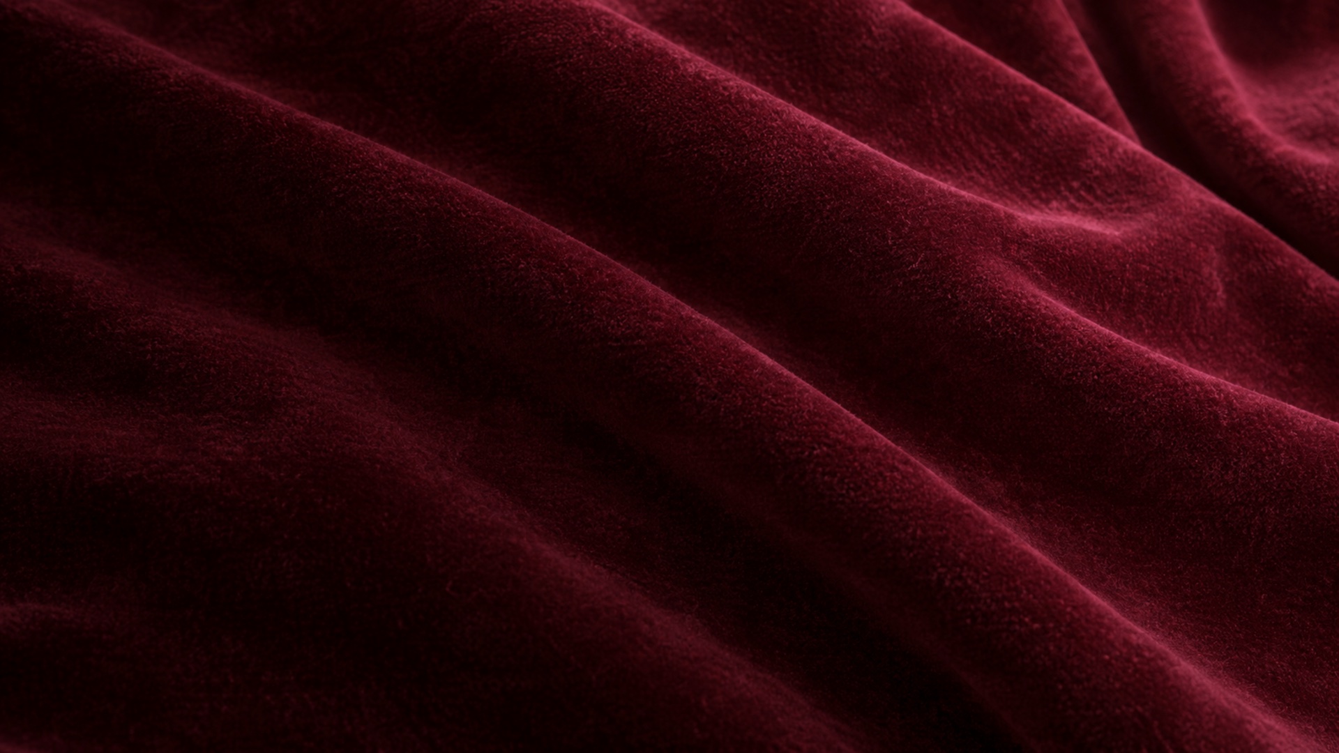 Close-up of burgundy cotton velvet in soft waves under grazing light